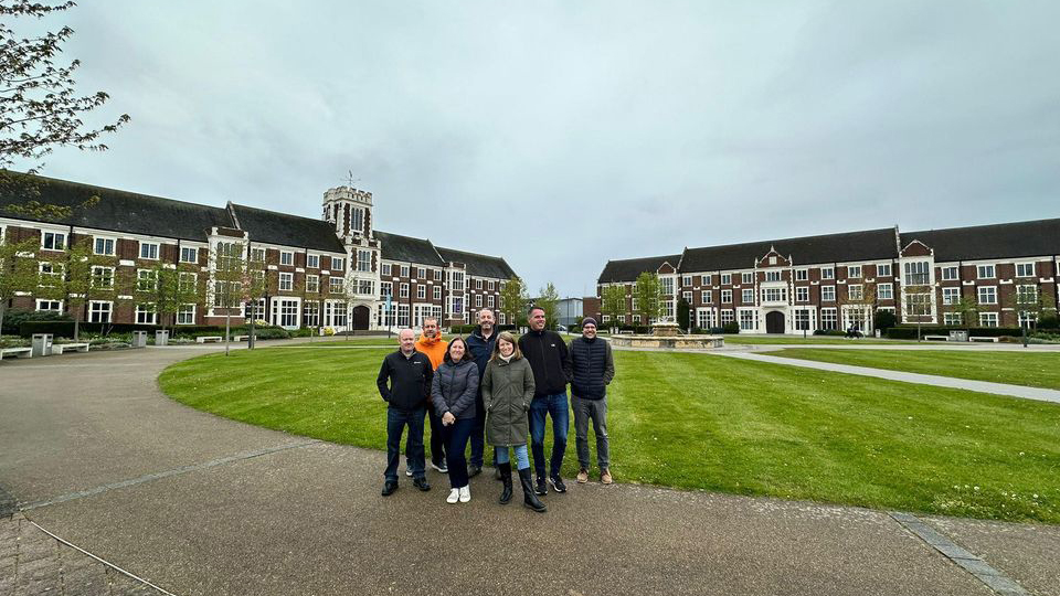 Group of alumni taking a picture in front of the Hazelrigg and Rutland buildings